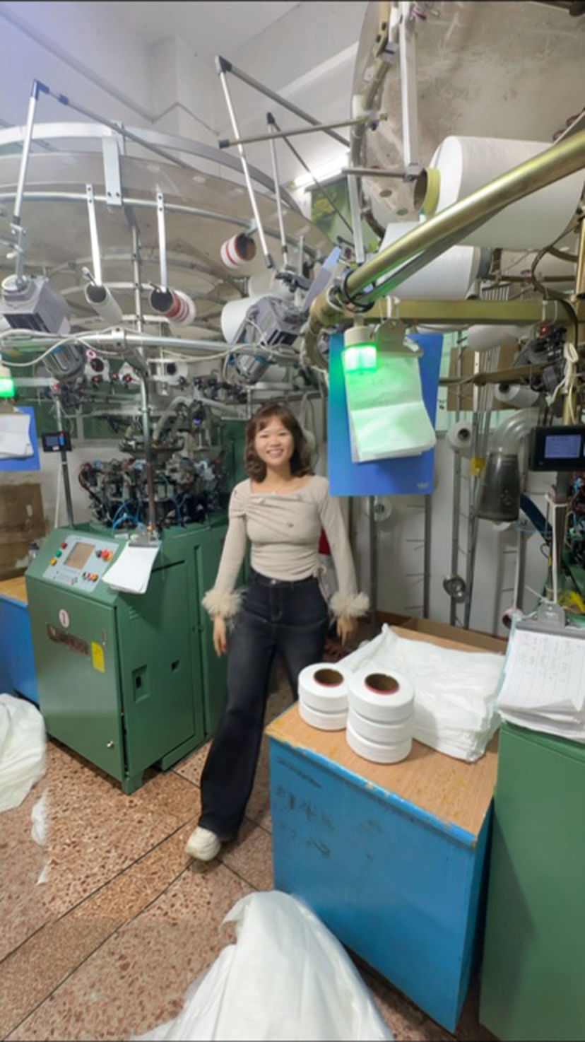 Gigi inside the GJ factory beside seamless knitting equipment
